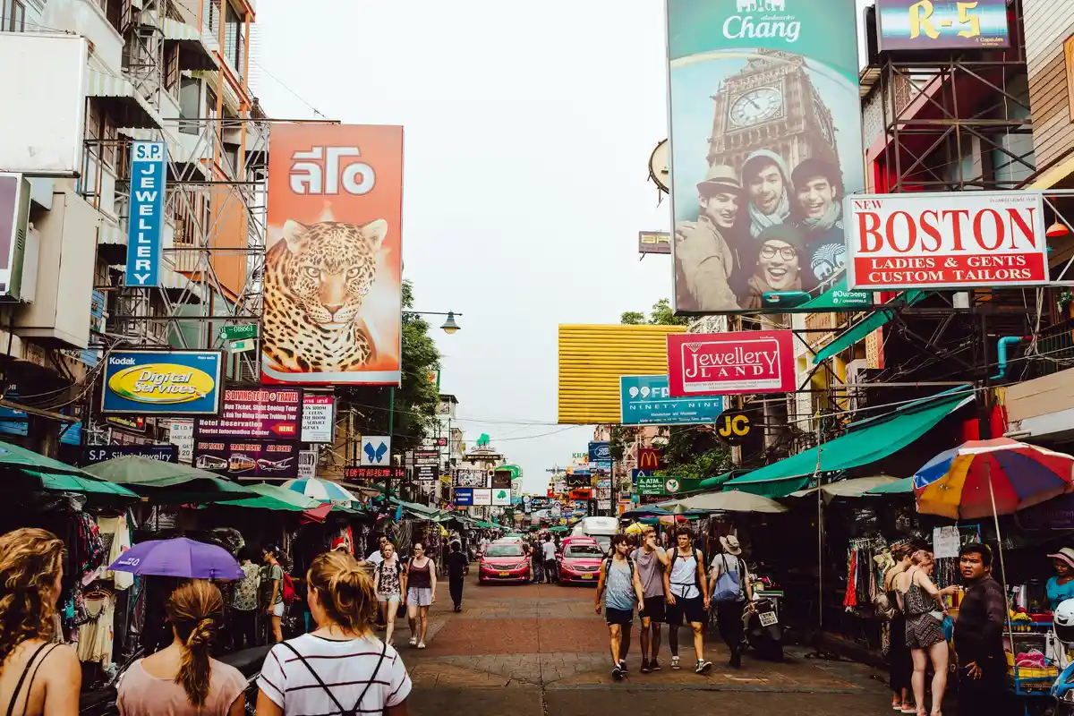 Bangkok street with market stalls, shop signs and pedestrians