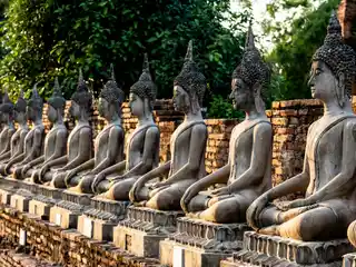 Rows of seated Buddha statues beside brick temple ruins in central Ayutthaya