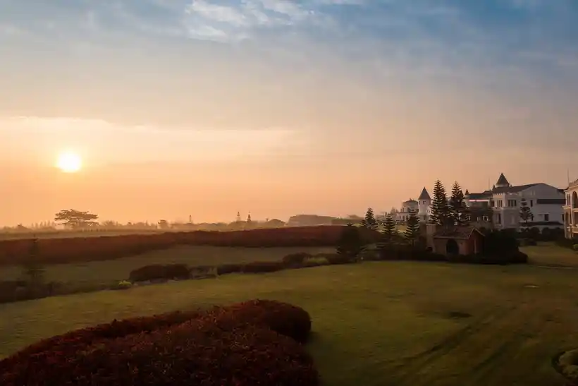 Sunrise over resort lawns, hedges, and low hills in Khao Yai